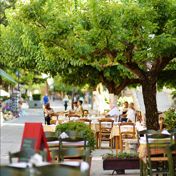 Small outdoor restaurants and cafes at the pedestrian area at center of Kalavryta town near the square and odontotos train station, Greece.