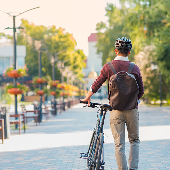 Male commuter wearing bike helmet walking away. Safe cycling in city, bicycle commuting, active urban lifestyle image